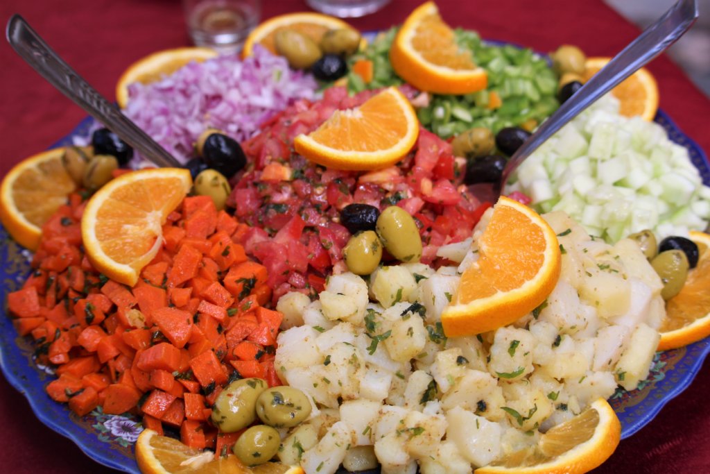 This photo shows a colourful Moroccan salad of diced vegetables garnished with slices of orange