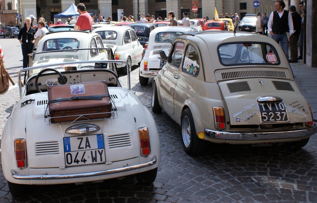 This photo shows a number of white and cream Fiat 500s making their way to the main square