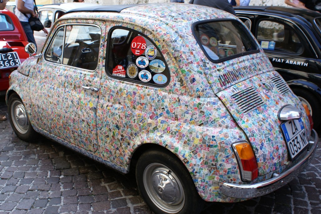 This photo shows a Fiat 500 completely covered in colourful postage stamps