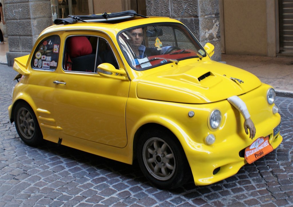This photo shows a canary yellow Fiat 500 with an apparenty severed arm trapped under the bonnet