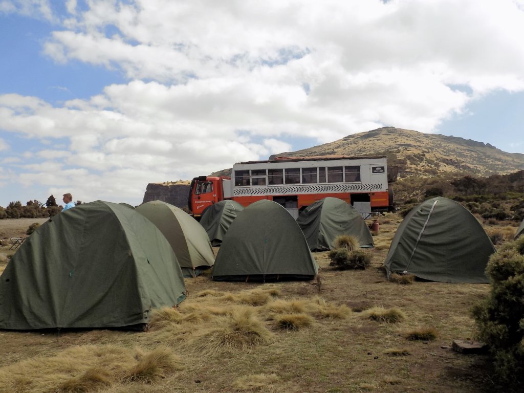 This photo shows our orange and white Dragoman truck with our tents pitched in front of it