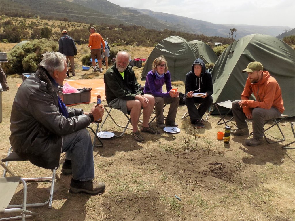 This picture shows several of our group sitting on low stools to eat their meal and have a beer