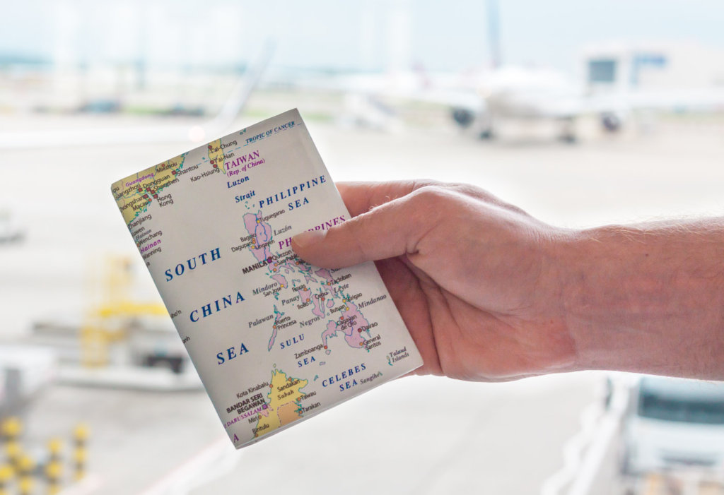 This photo shows an extended hand holding a passport Amigo travel wallet 