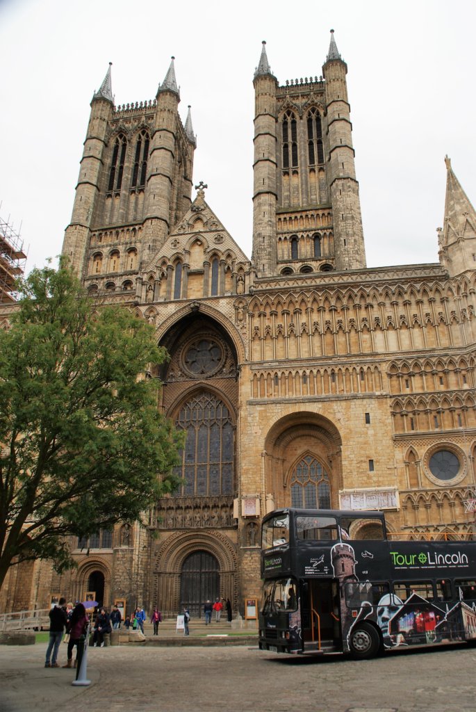 This photo shows an open-top bus parked in front of Lincoln Cathedral
