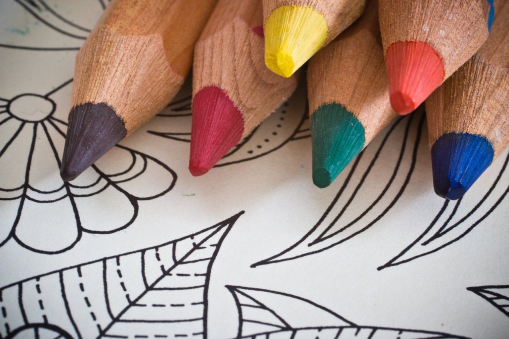 This picture shows the tips of 6 coloured pencils resting on a colouring page