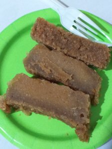 This photo shows three slices of cassava pone on a green paper plate