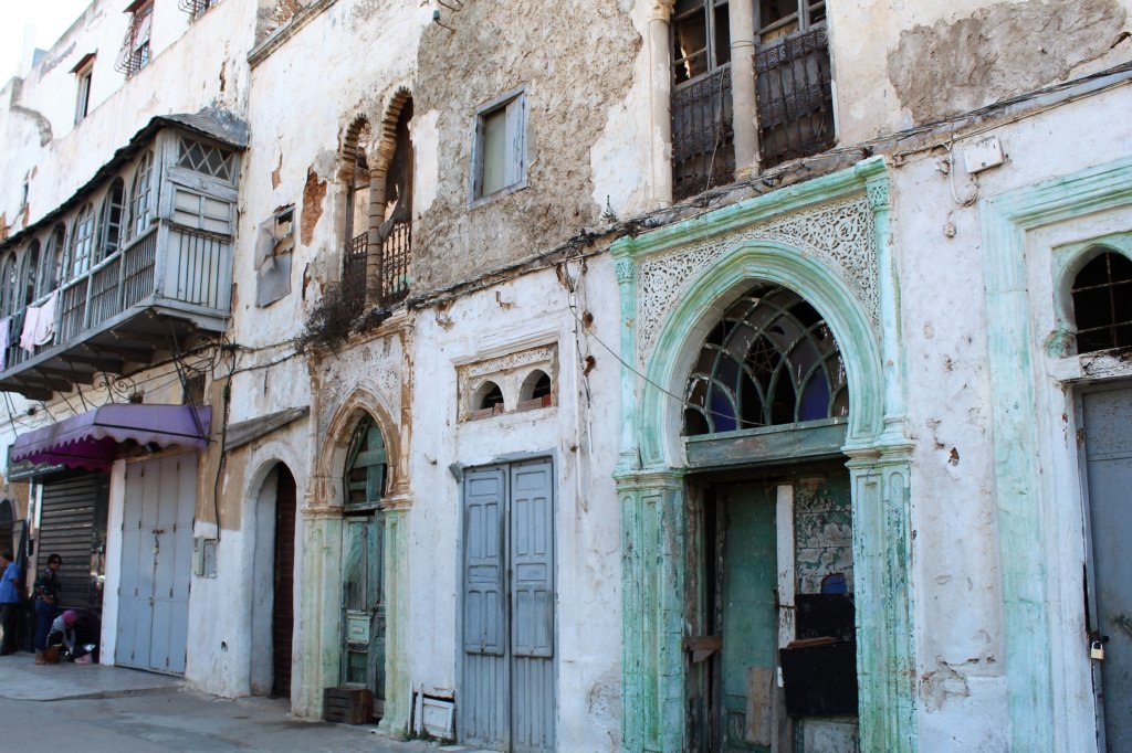 This photo shows a building with broken windows and crumbling plasterwork