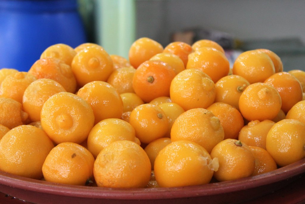 This photo shows a bowl of vibrant golden yellow preserved lemons
