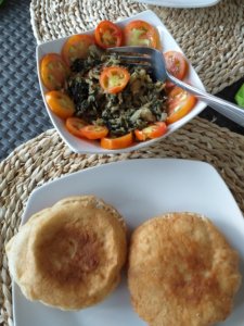 This photo shows a bowl of salt fish mixed with fitweed with slices of tomato to garnish