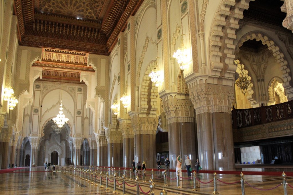 This photo shows the lavish interior of Hassan II Mosque with its high ceilings and ornate candelabras