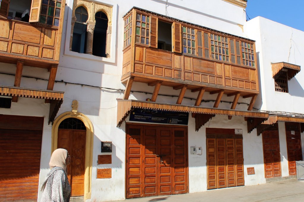 This photo shows stained wooden doors and windows set against a white plastered building