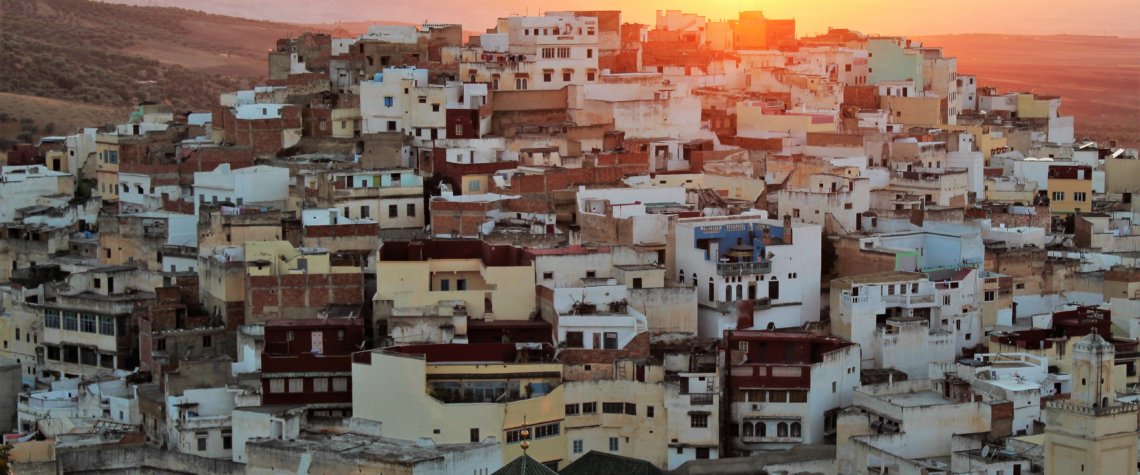 This photo shows the sun setting behind the hill beyond Moulay Idriss