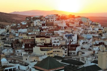 This photo shows the sun setting behind the hill beyond Moulay Idriss