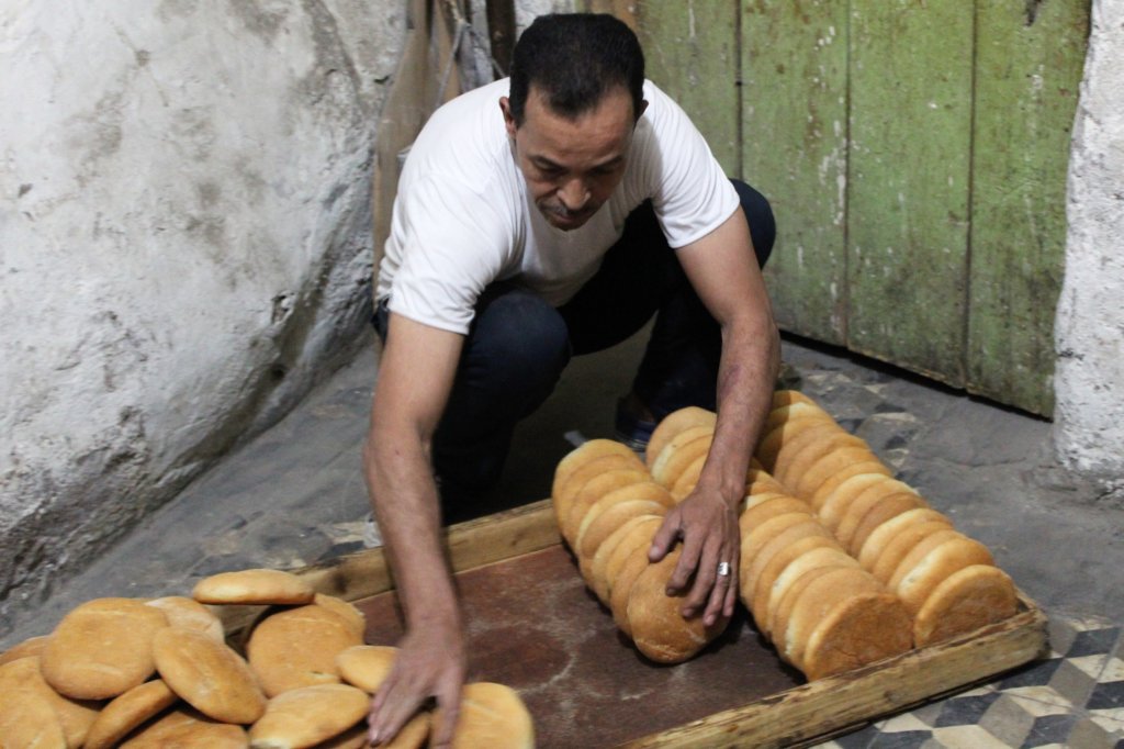 This photo shows the baker packing rolls into a shallow wooden tray ready for the local restaurants
