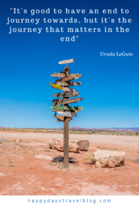 This photo shows a signpost in the desert with a travel quote by Ursula Le Guin, 'It's good to have an end to journey towards, but it's the journey that matters in the end.'