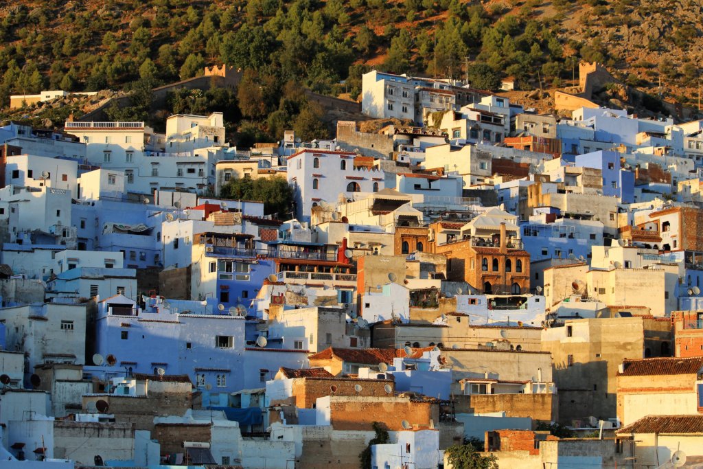 This photo shows blue and white houses bathed in the glow of the setting sun