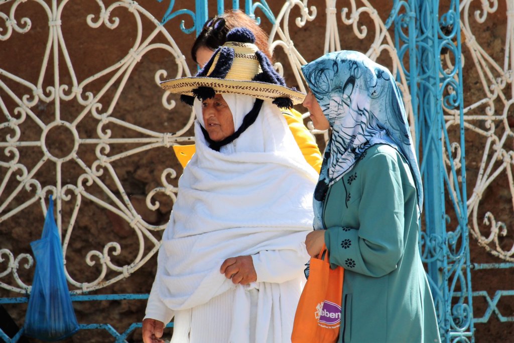 This photo shows a Chefchaouen lady in traditional costume walking between two friends in the main square