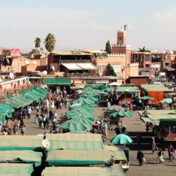 This photo shows Djemaa el-Fna with lots of stalls topped with green tarpaulins or umbrellas