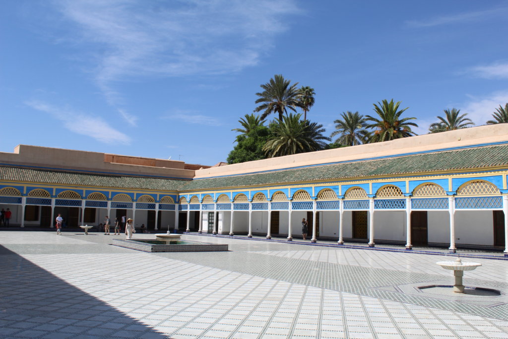 This photo shows the main courtyard in Bahia Palace with its white marble floor and decorative blue and gold pergolas around the outside