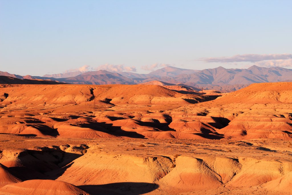 This photo shows dunes and hills turned orange by the rays of the setting sun