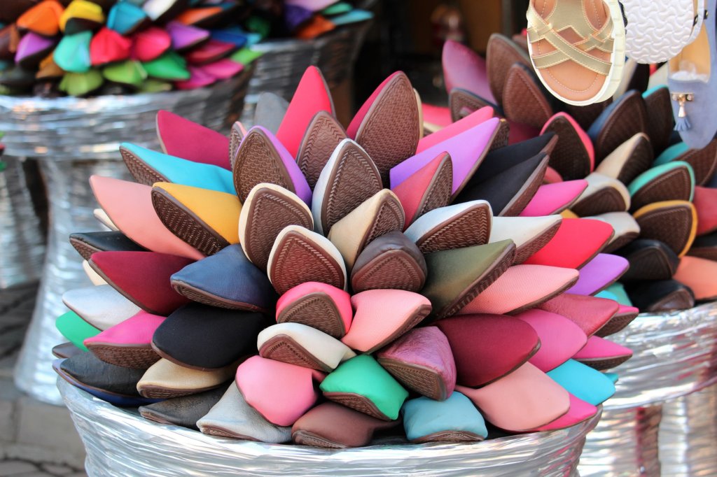 This photo shows a basket of artfully arranged leather slippers in many different colours on sale in the souk