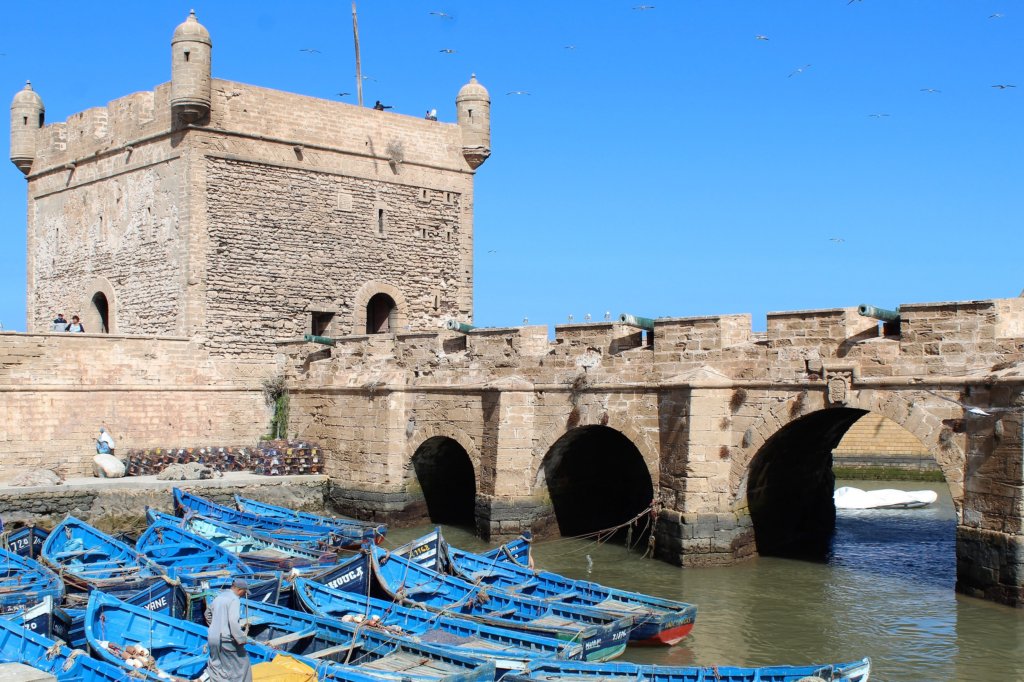 This photo shows part of the harbour with small local boats painted bright blue and the town's ramparts behind