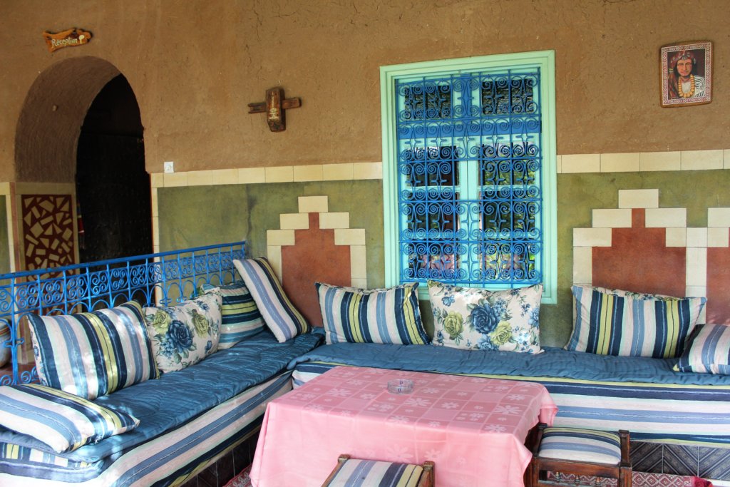 This photo shows a seating area with a highly decorative window and colourful cushions