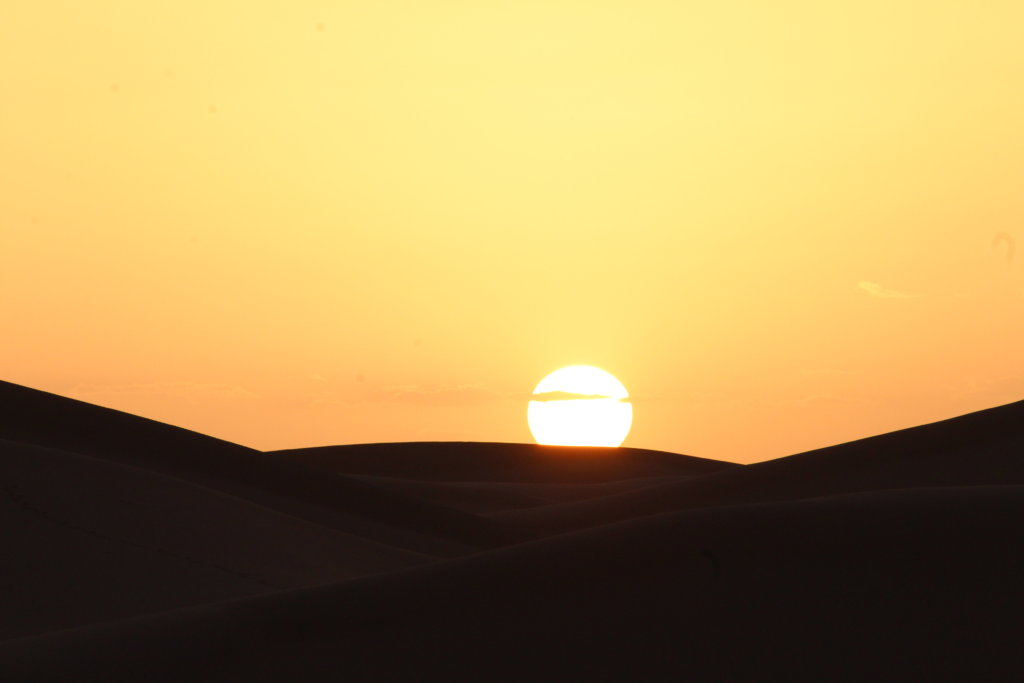 This photo shows the sun setting behind a dune