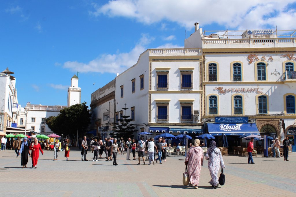 This photo shows the main square in Essaouira with pavement cafes and ladies shopping