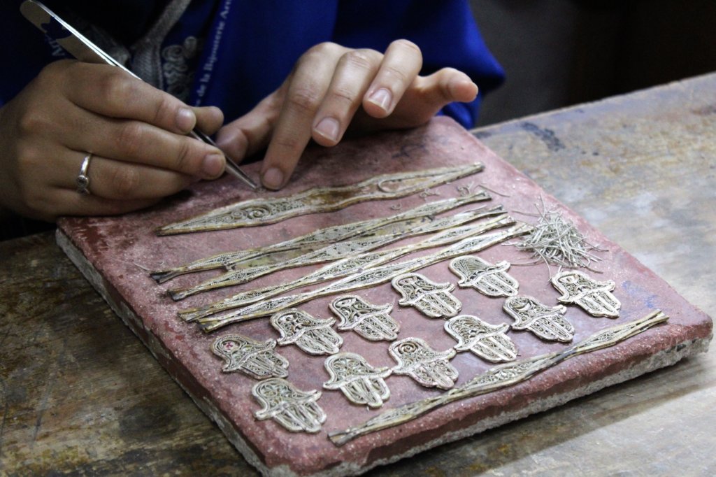 This photo is a close-up of a girl making intricate designs in fine silver