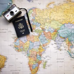 This picture shows a wworld map with a camera and passport on it