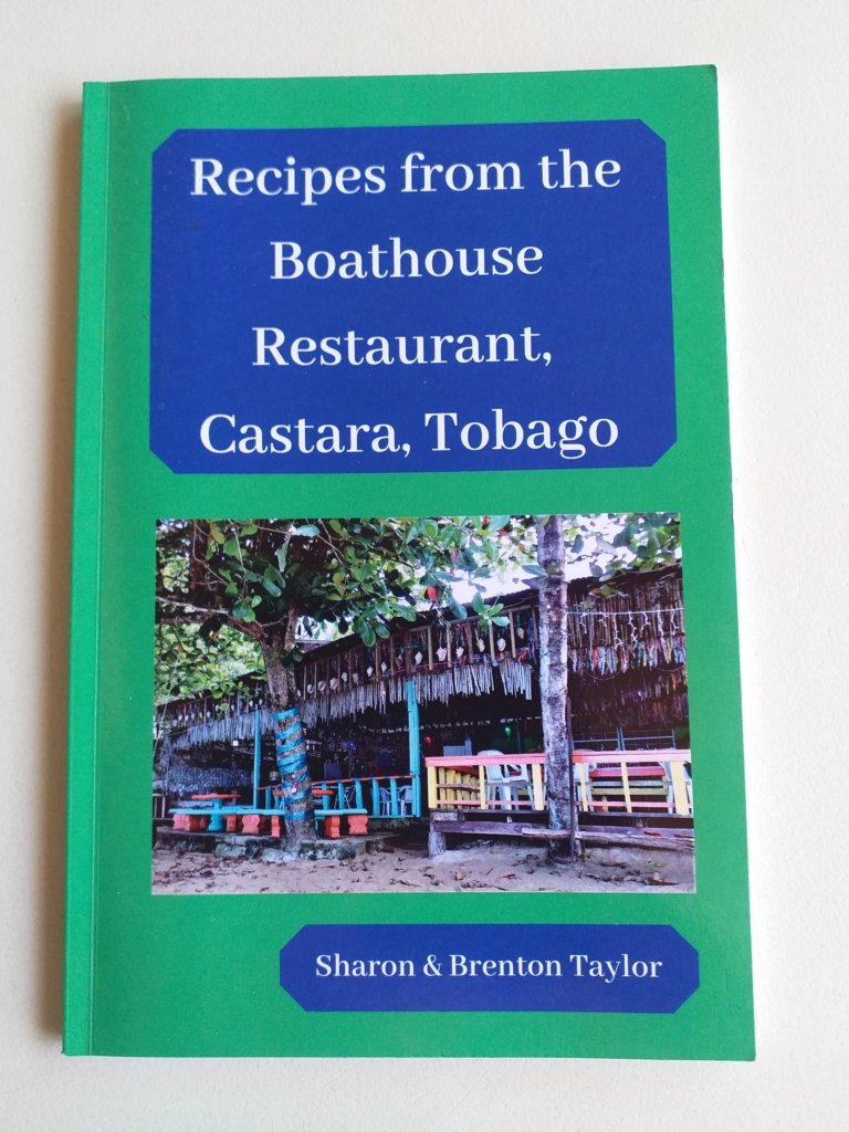 This photo shows the cover of the Boathouse cookbook with a photo of the beachfront restaurant