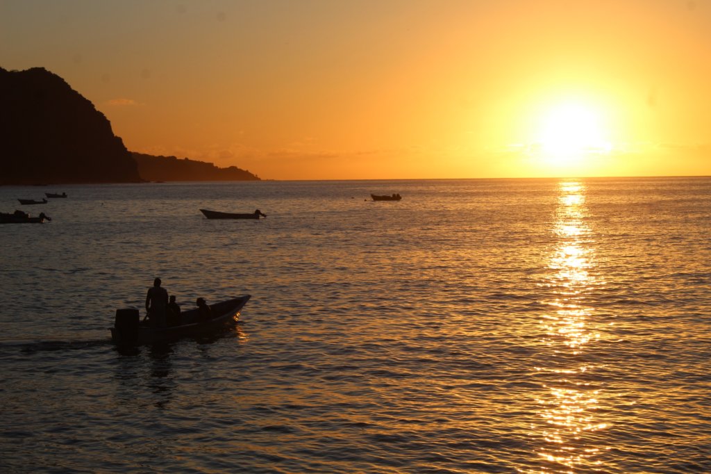 This photo shows a glorious orange sun setting behind the Caribbean Sea
