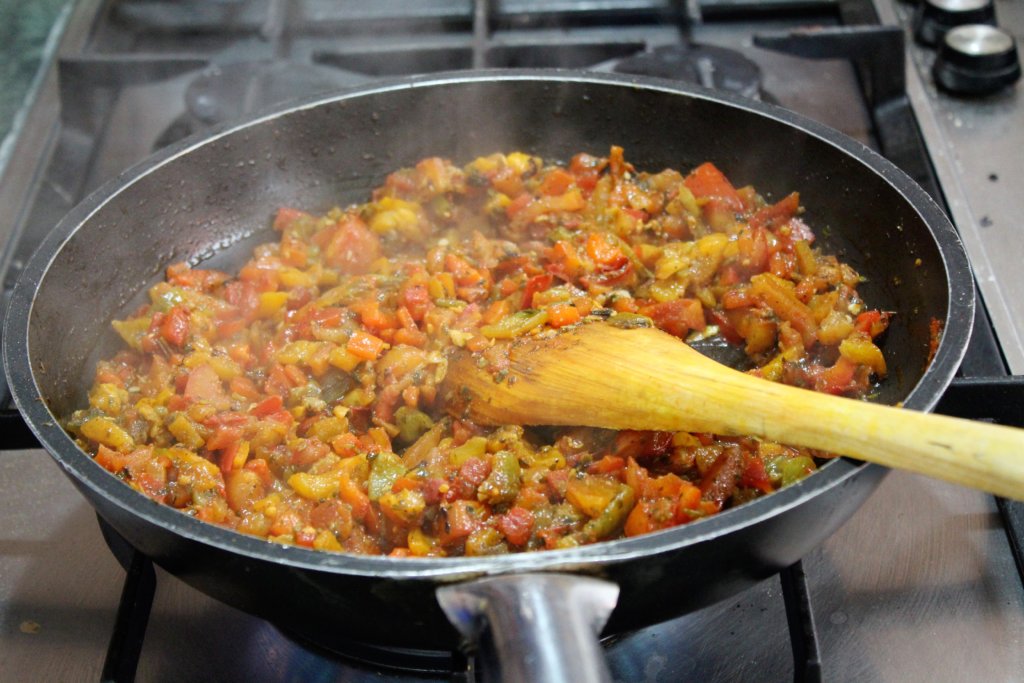 This photo shows a pan of simmering finely diced tomatoes and aubergines