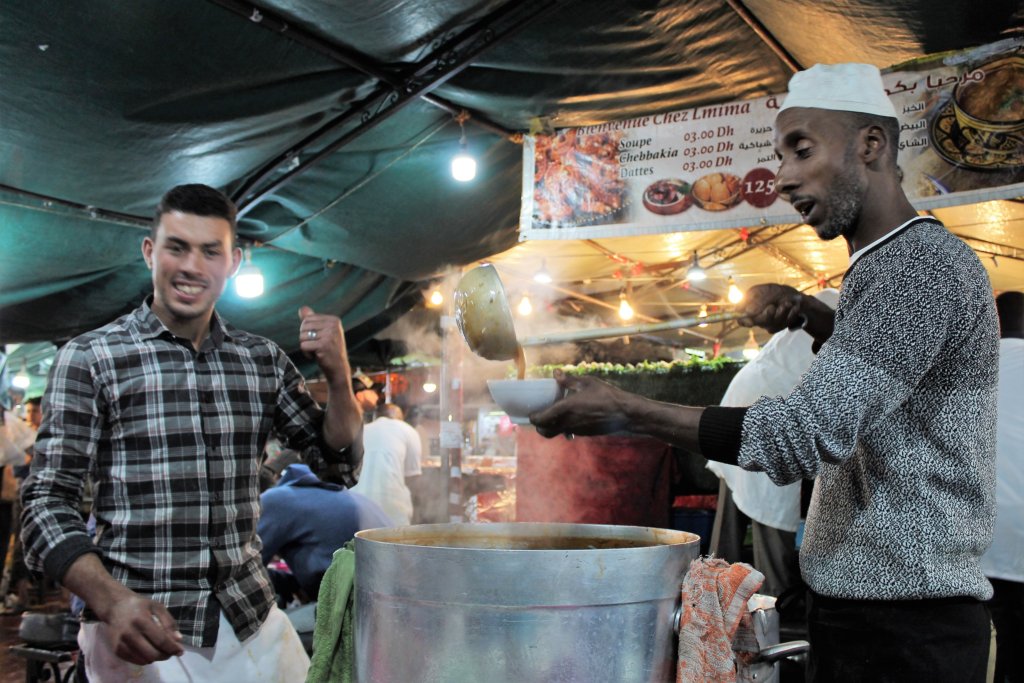 This photo shows two guys on a harira stall in Marrakech. One of them is flambouantly ladelling soup into a bowl.