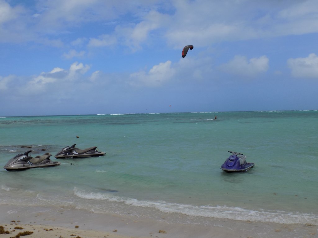 This photo shows one kiteboarder and three jet skis