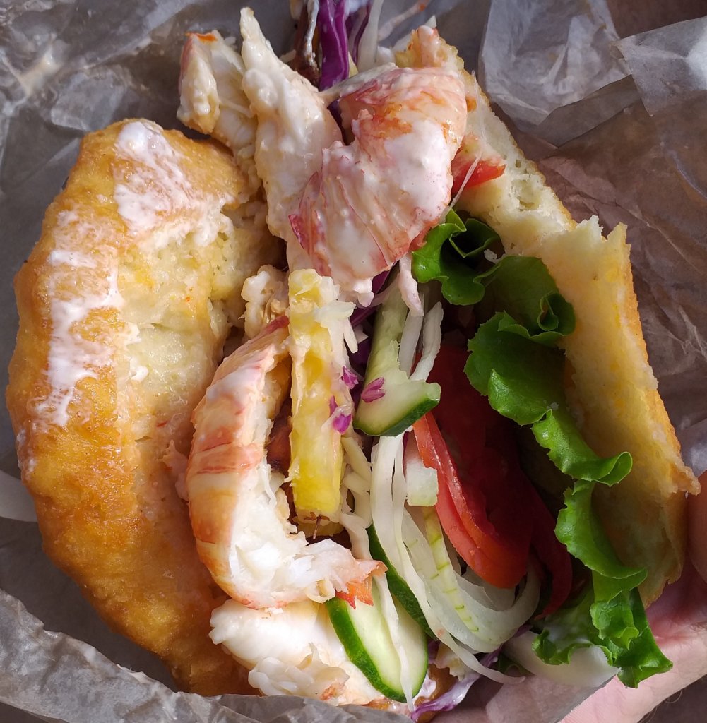 This photo shows a round sandwich stuffed with barbecued langoustine and fresh salad