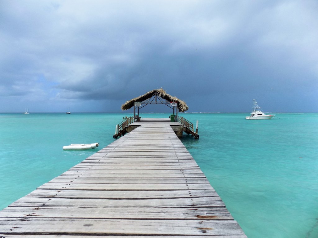 This photo shows a wooden jetty with a thatched shelter at the end of it