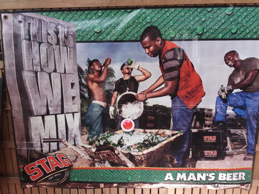 This photo shows an advertising poster for Stag lager with workers mixing concrete while drinking the beer