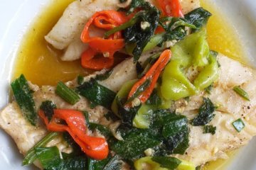 This photo shows fish topped with herbs and chillies