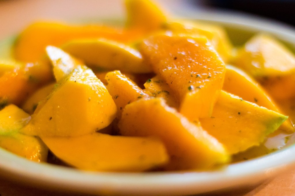 This photo shows a dish of vibrant fresh mango pieces seasoned with pepper