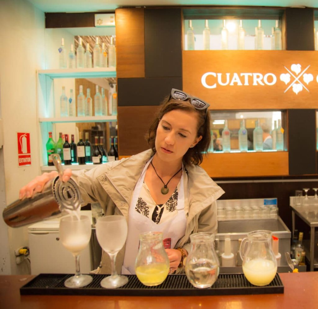 This photo shows a lady pouring drinks into different-sized glasses 