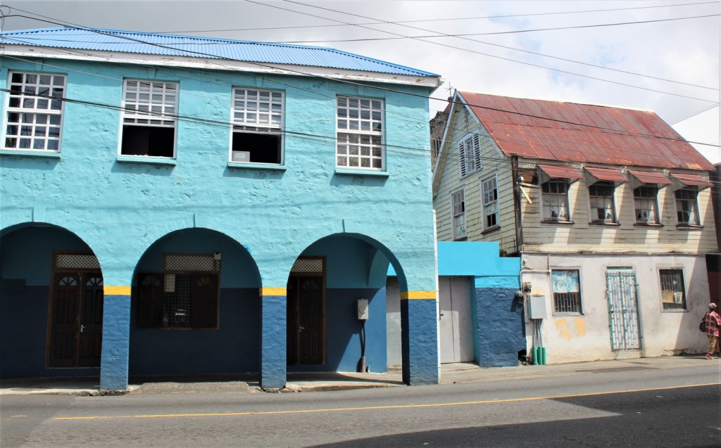 This photo shows two old buildings in Kingstown, one of them is painted blue and has lots of arches