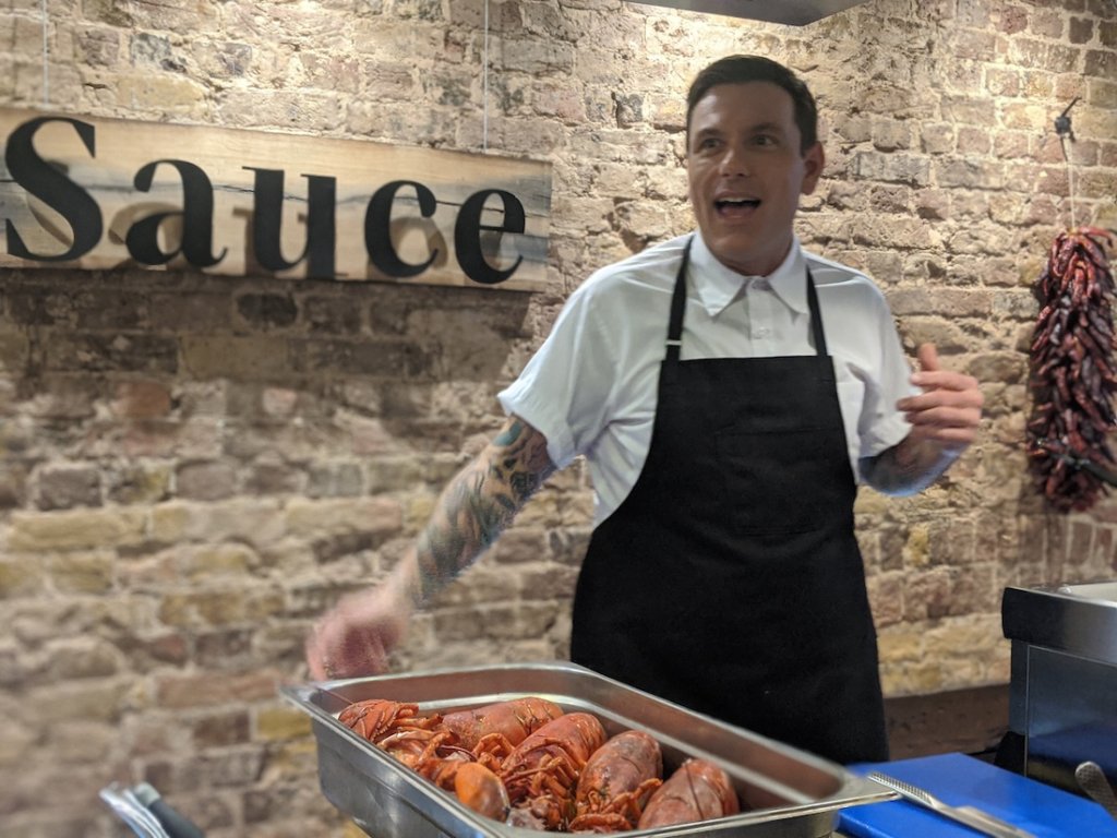 This photo shows a chef with a tray of lobster ready to prepare his dish