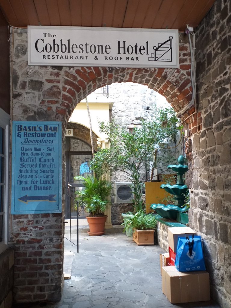 This photo shows a brick archway leading to the Cobblestone Inn with a sign pointing to Basl's Bar on the left