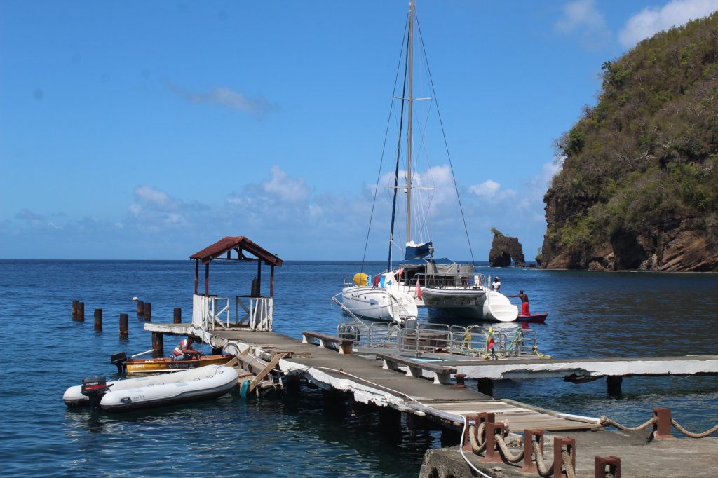 This photo shows a wooden jetty with a catamaran behind it