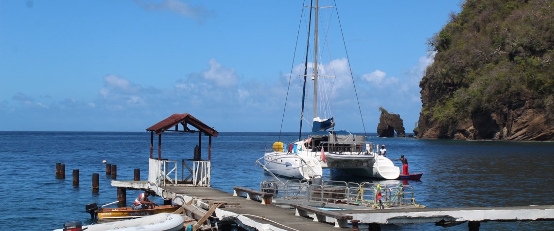 This photo shows a wooden jetty with a catamaran behind it