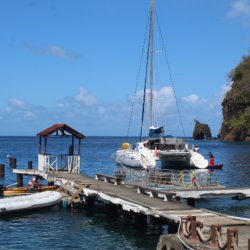 This photo shows a wooden jetty with a catamaran behind it