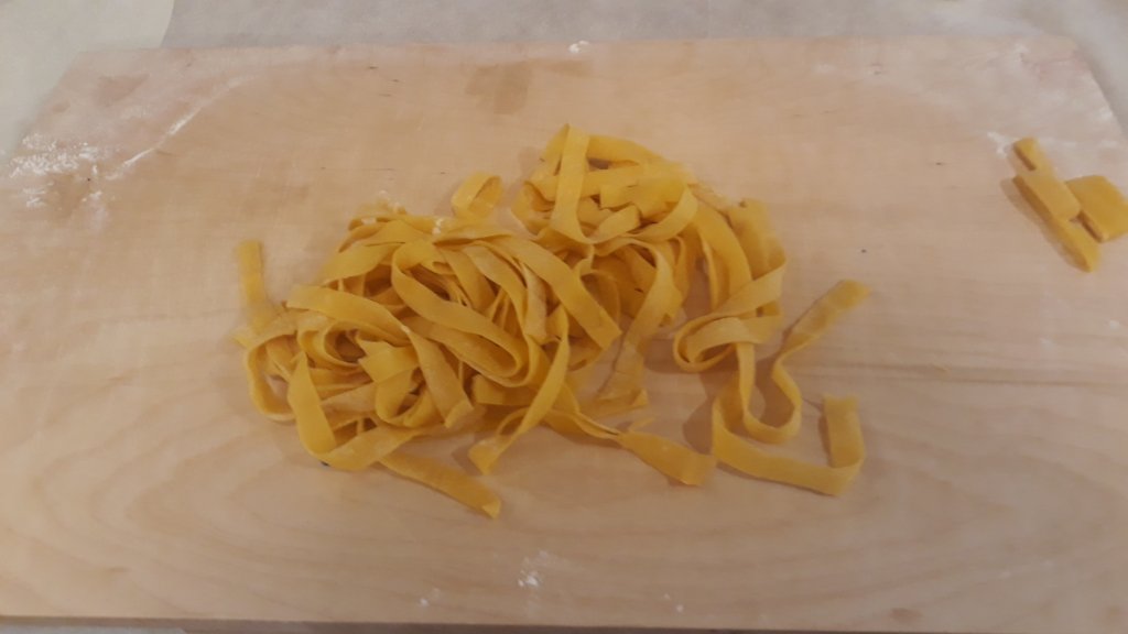 This photo shows a pile of freshly-made tagliatelle on a floured board