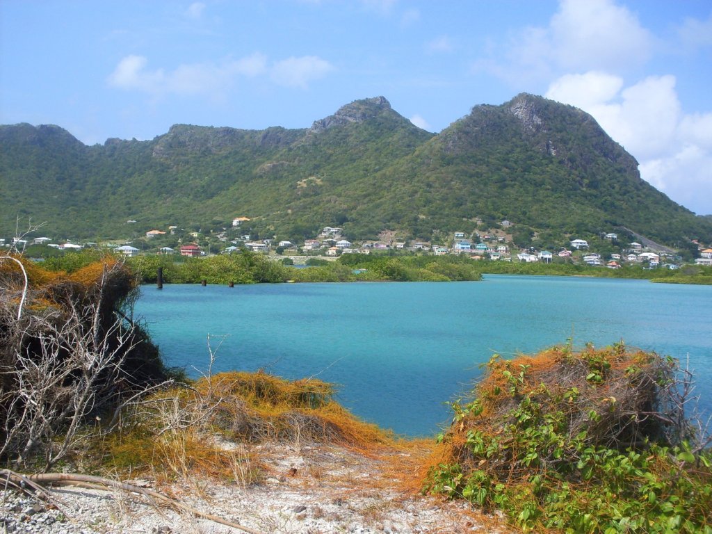 This photo shows a bay with clear blue water surrounded by verdant mountains